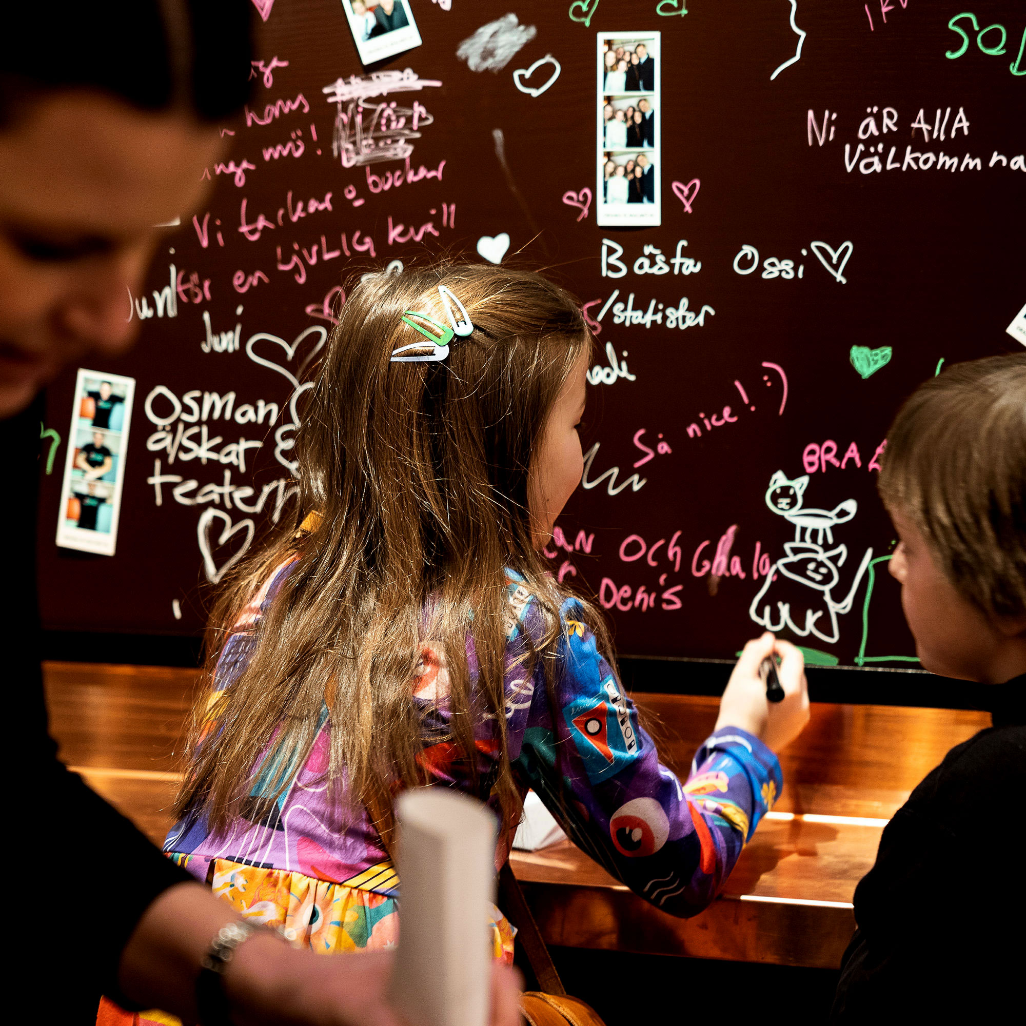 Barn klottrar med färgade pennor på en vägg i foajén.