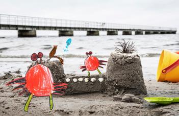 Ritade krabbor på en riktig sandstrand vid ett sandslott