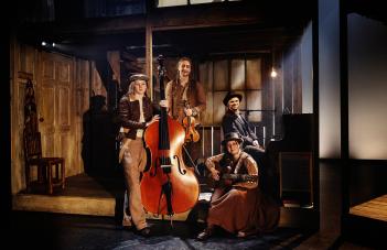 Fyra musiker står med sina instrument: kontrabas, fiol, piano och gitarr.