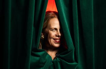 Porträtt på Petra Brylander. Kikar fram bakom en grön ridå.