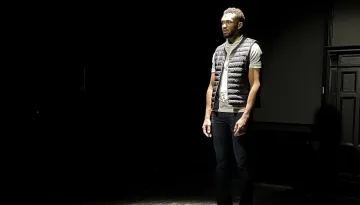 En manlig skådespelare i helfigur i ett naket scenrum