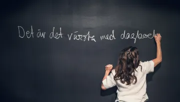 Person med ryggen mot skriver på en stor griffeltvla