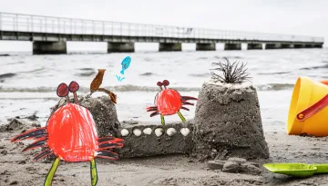 Ritade krabbor på en riktig sandstrand vid ett sandslott