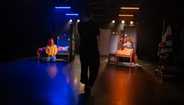 En fotograf i siluett i förgrunden som fotar en föreställning på en liten scen