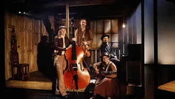 Fyra musiker står med sina instrument: kontrabas, fiol, piano och gitarr.