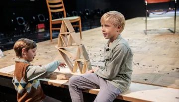 Två pojkar leker med korthus på scen