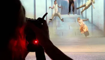 Föreställningsfotografen Emmalisa Pauly syns i förgrunden med kameran riktad mot scenen under fotografering av Ett drömspel på Hippodromen 2024. På scenen hänger och flyger skådespelare och cirkusartister i en blåskimrande, drömlik miljö.