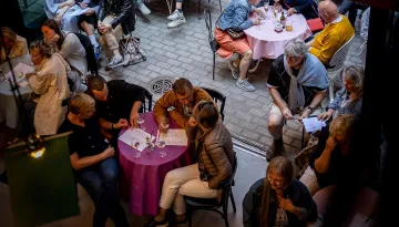 Personer sitter runt runda bord med färgglada dukar och diskuterar