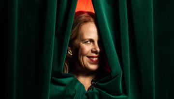 Porträtt på Petra Brylander. Kikar fram genom en grön ridå.