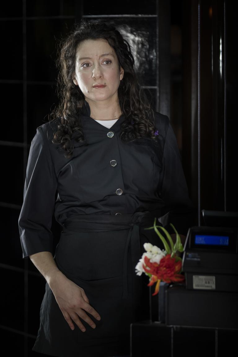 En kvinna stående i svarta restaurangkläder