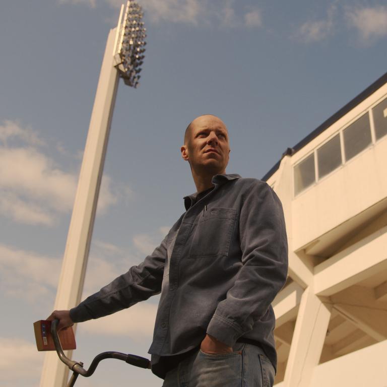 Man står med cykel framför Malmö fotbollsstadium 