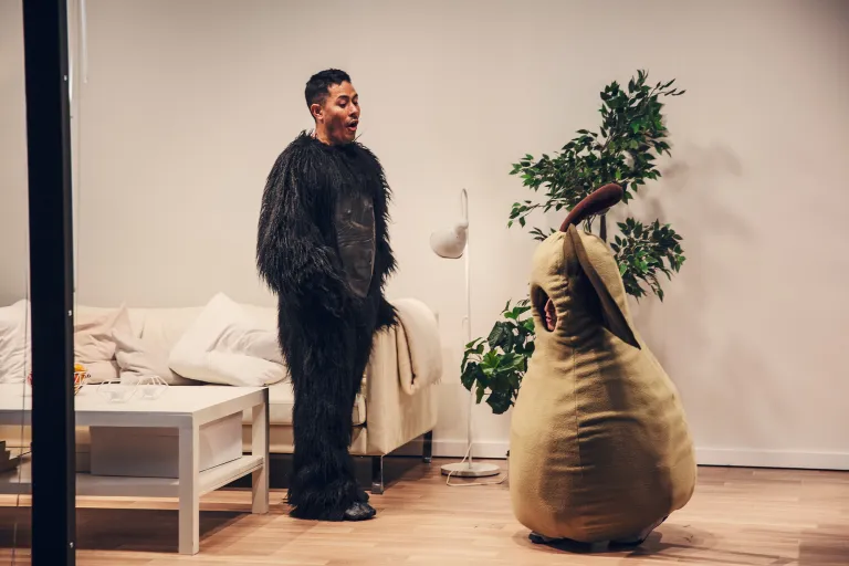 En man i gorillakostym står bredvid en kvinna som sitter på huk i en päronkostym