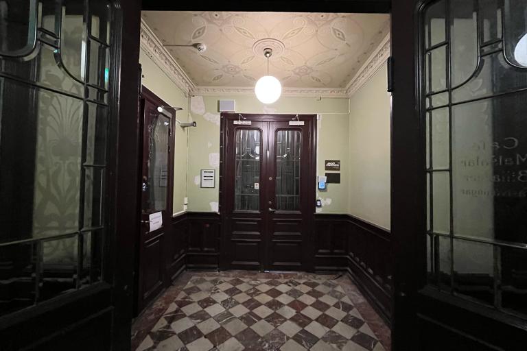 entréhall Kalendegatan 12b. två bruna portar med glasfönster, marmorgolv, stukatur i tak och pendel-lampa