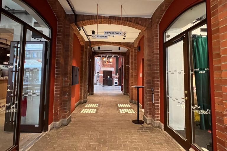 Gång Kalendegatan 12c, tegelgolv och väggar, stora fönsterparti in till café vänster, ateljé höger. Innergård skymtar rakt fram