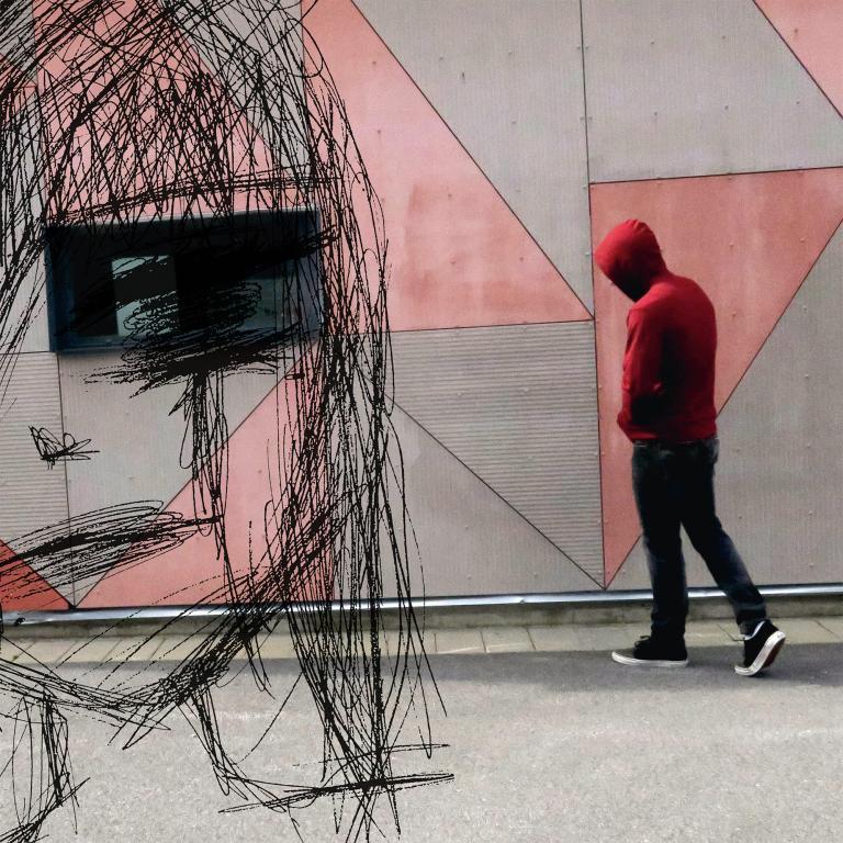 Tonåring med hoodie går förbi grafittivägg