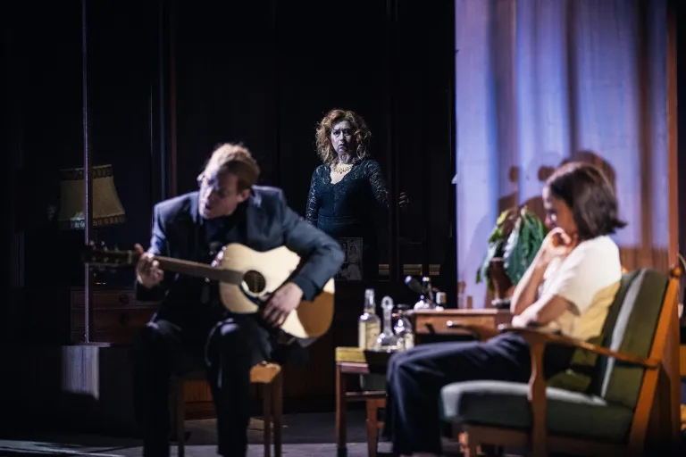 Person med gitarr till vänster, en som lyssnar till höger. I bakgrunden fokus på en person.