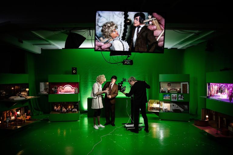 Ett green-screenrum med skådespelare och en tv-skärm