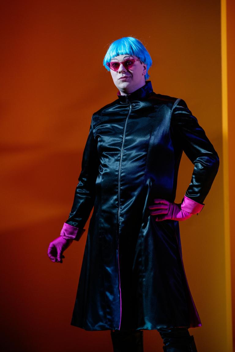 Föreställningsbild Kejsarens nya kläder. Skräddaren i blank svart kostym och blå peruk