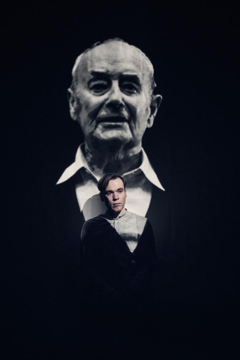 Föreställningsbild Stefan skådespelare sitter framför en projicerad bild på den verkliga Stefan Zablocki