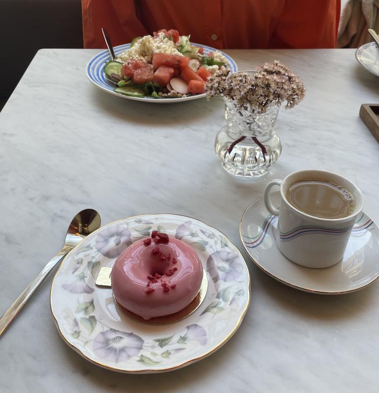 En rosa bakelse med en kopp kaffe