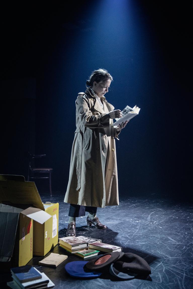 Kvinna stående i trench coat läser något.