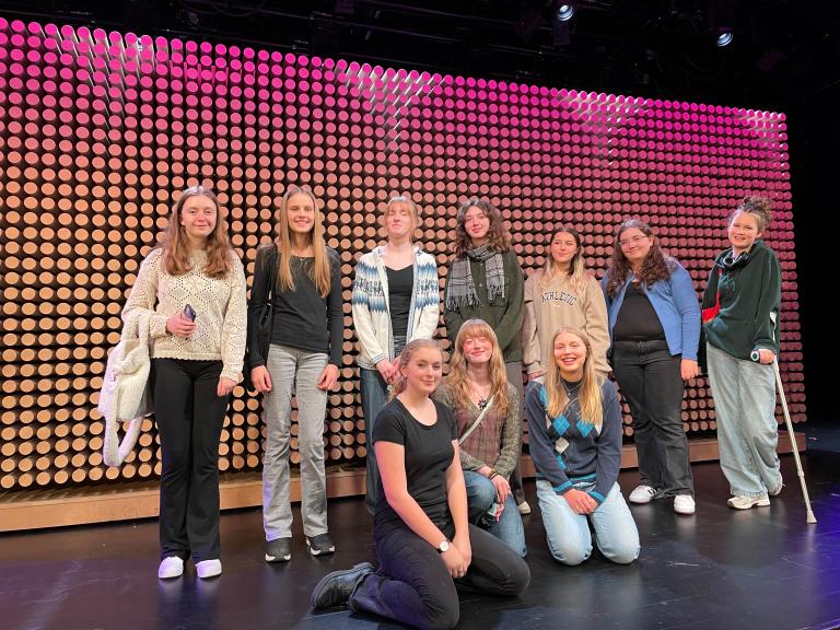 Gruppbild Lomma ensemble. ungdomar framför scenografi i rosa och gul 