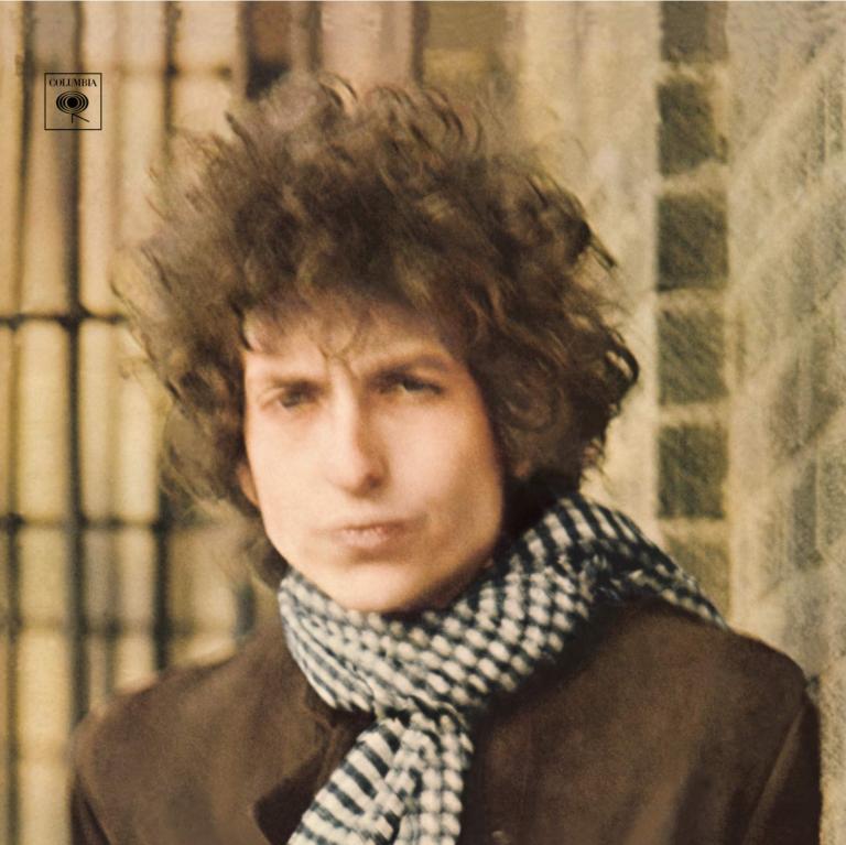 Skicomslag med bild på Bob Dylan med ruffsig frisyr i brun rock och svart vit rutig halsduk.