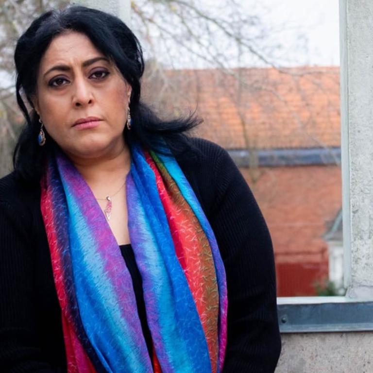 Bissan Edwan Porträttbild, en kvinna med svart långt hår, svart tröja och färgglad scarf tittar allvarligt in i kameran