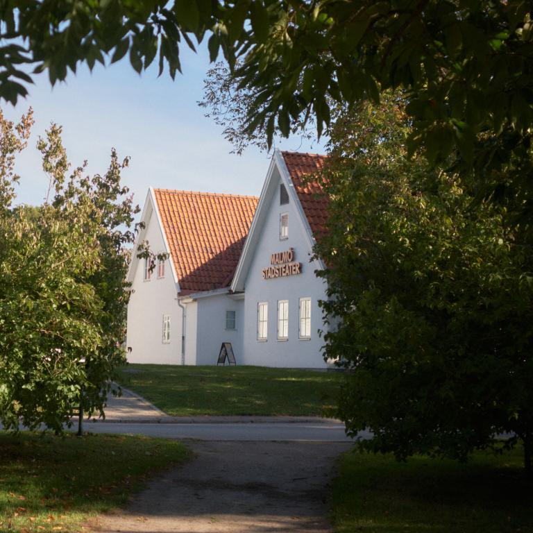 Exteriör bild Malmö Stadsteater Rosengård. Vitputsat hus med tegeltak, stor skylt Malmö Stadsteater