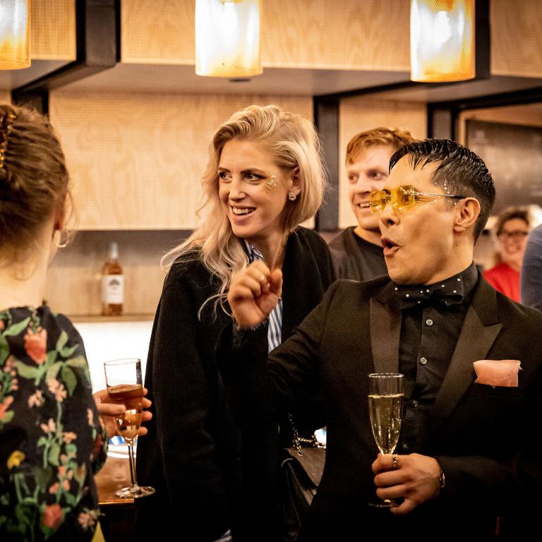 Foto: Jenny Baumgartner Ett gäng socialiserar och dricker bubbel i teaterfoajén