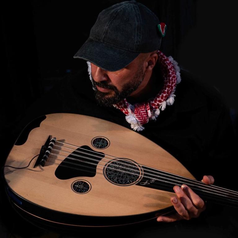 Ole V. Wagner Person som sitter nedböjd över en oud, ett stränginstrument.