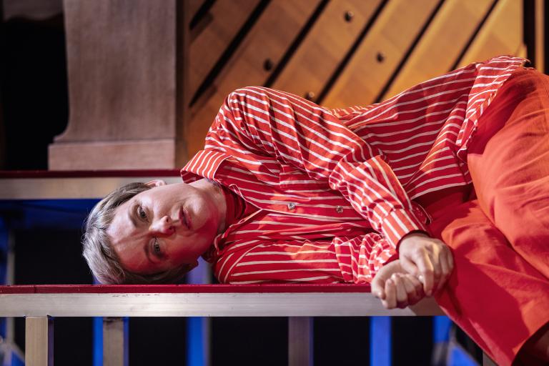 Person ligger på sidan på en upphöjd plattform i randig röd skjorta.