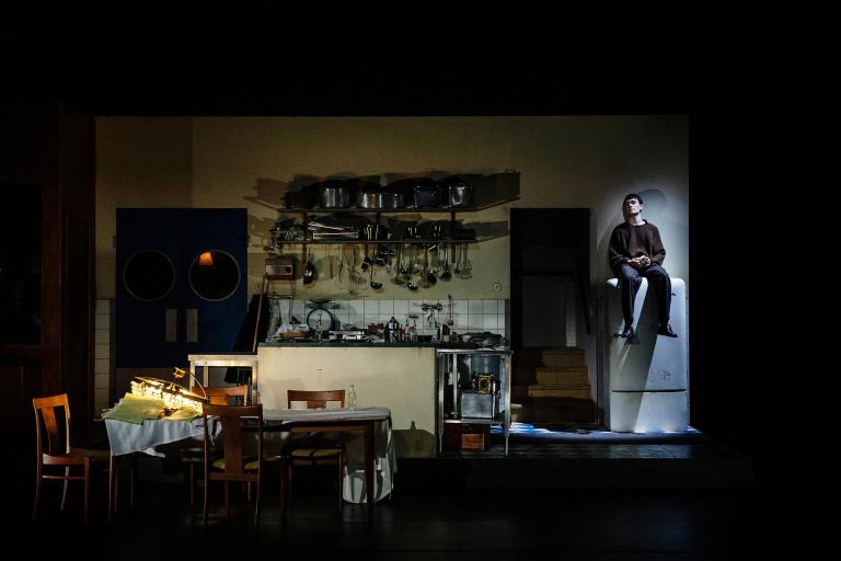 Person sitter ovanpå ett kylskåp till höger i bild.