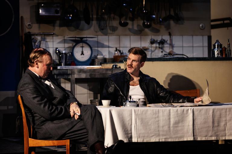 Två personer sitter vid ett matbord och pratar