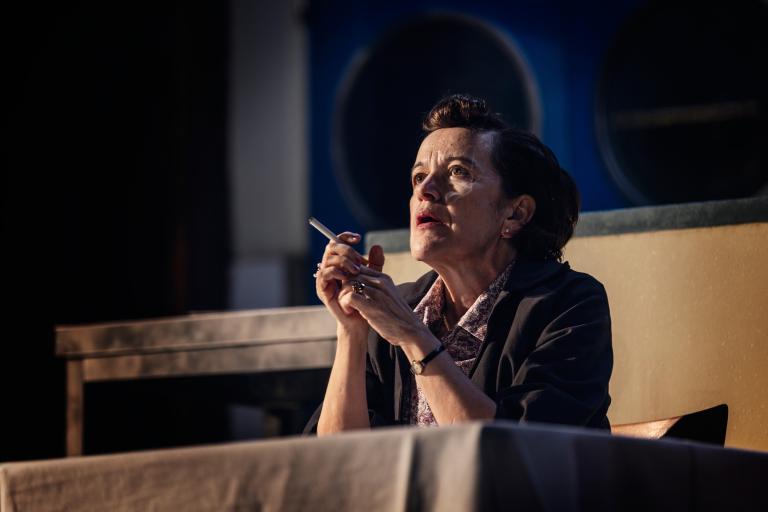 En person vid ett bord med cigarett i handen.