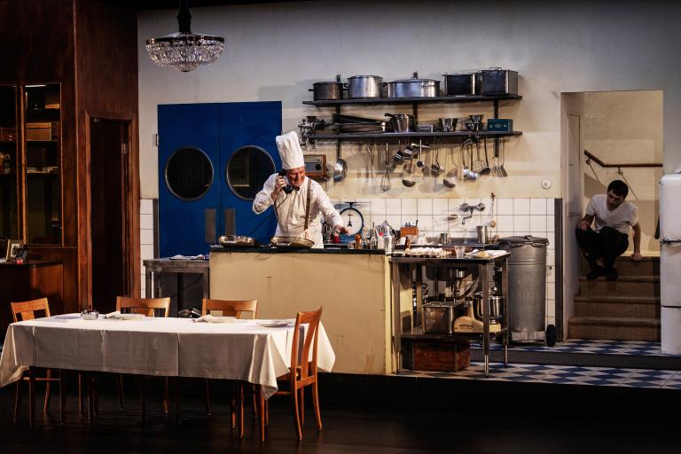 En person i kockkläder lagar mat i ett stort restaurangkök