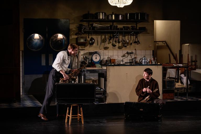 Två personer fixar med två saxofoner