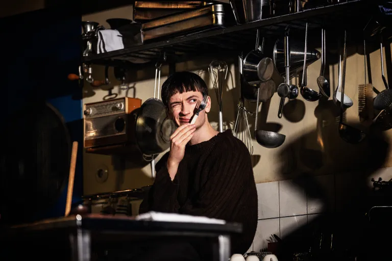 En person i ett kök håller en gaffel framför ansiktet