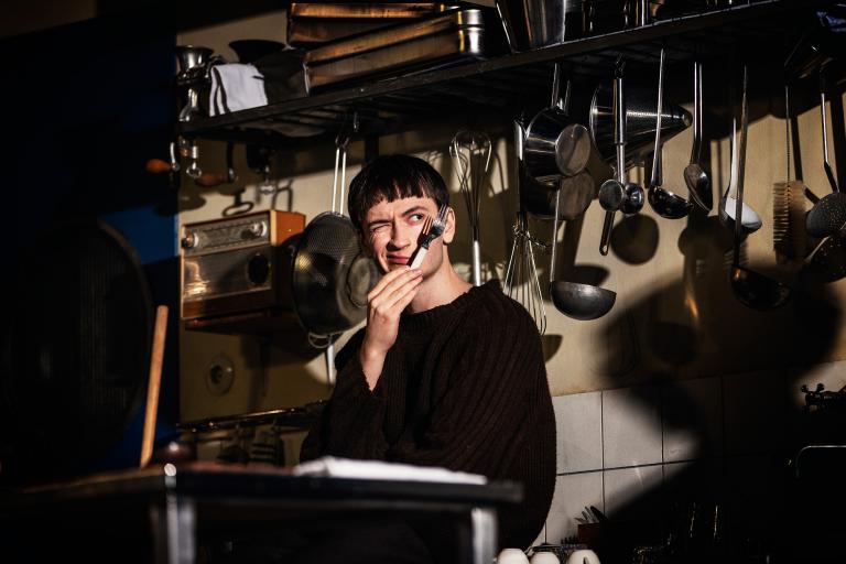 En person i ett kök håller en gaffel framför ansiktet