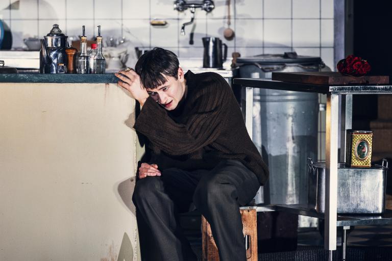 En person sitter och lutar sig mot en bänk