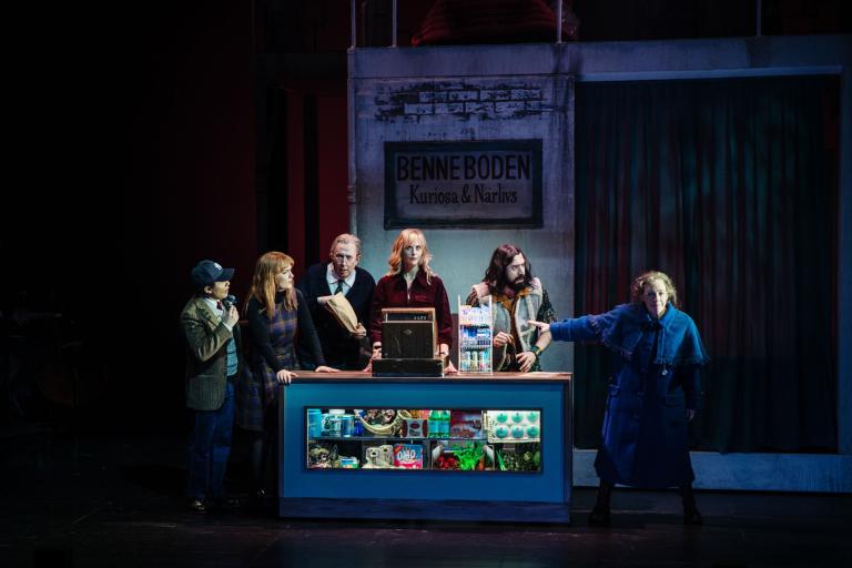 Flera personer står samlade vid en butiksdisk med skylten “Benneboden Kuriosa & Närlivs”.