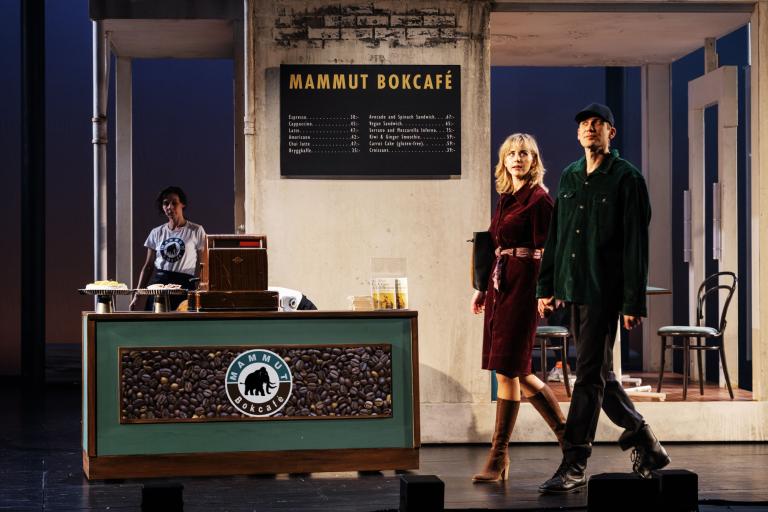 Två personer går förbi en kafédisk med skylten “Mammut Bokcafé”.