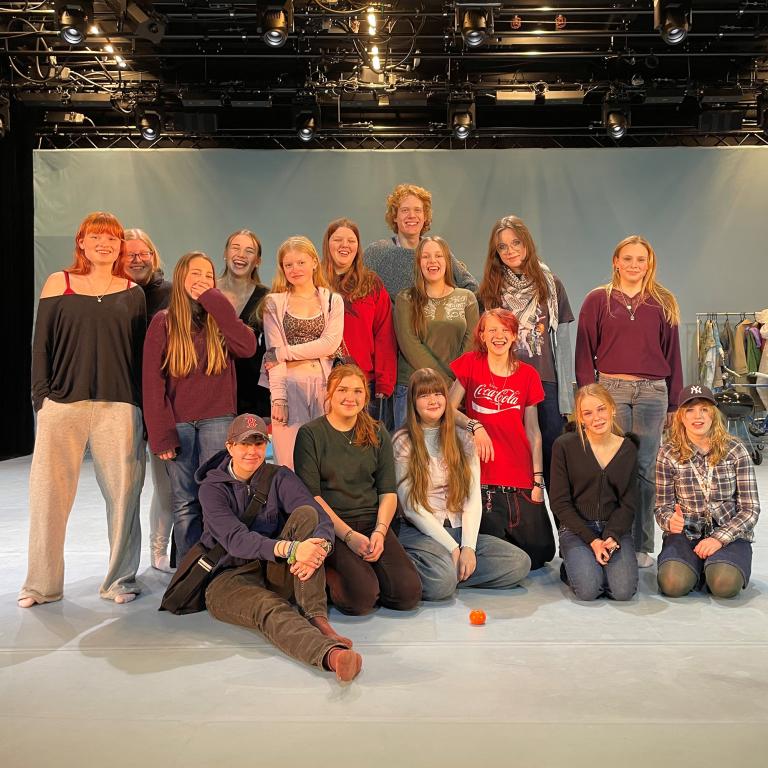 Gruppbild på ungdomar som står i en scenografimiljö