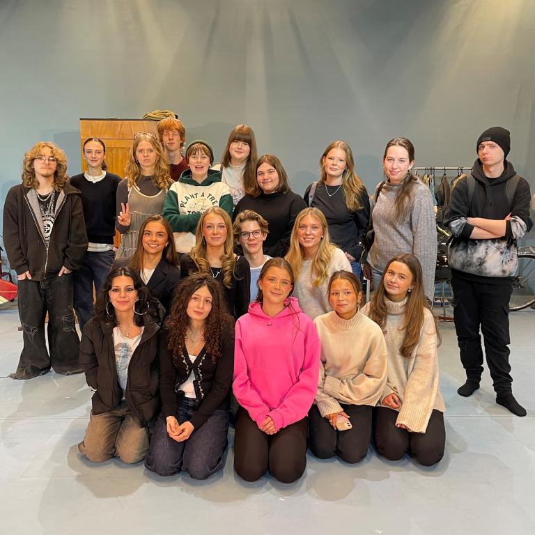 Gruppbild på ungdomar som står i en scenografimiljö