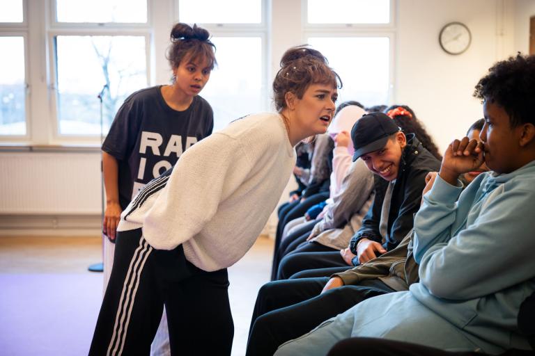 två skådespelare interagerar med publik som fnissar. 