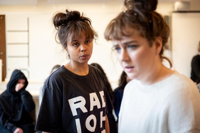 två skådespelare med hårknut och svartvita kläder tittar i olika riktningar