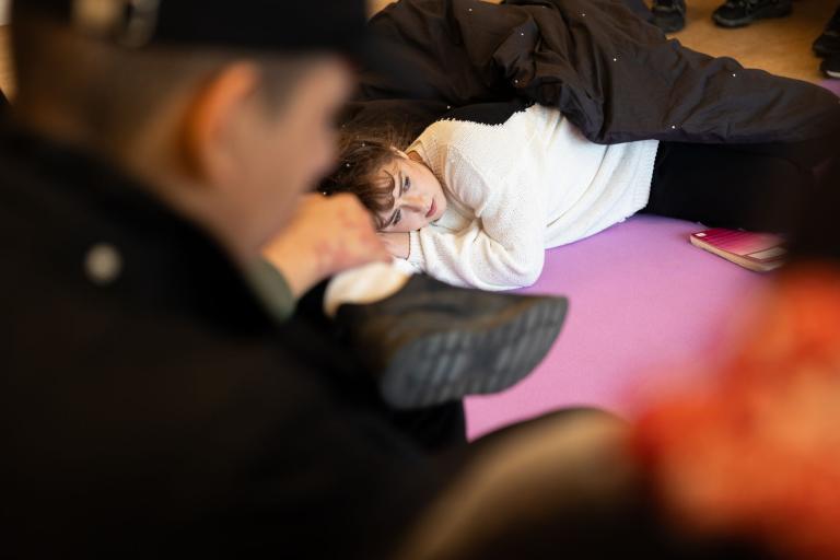 i förgrunden publik, bakom på golvet en skådespelare som ligger ner. 