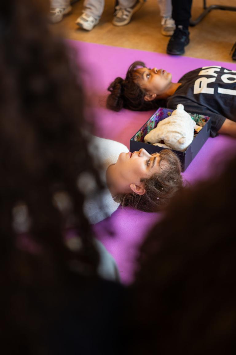 två skådespelare ligger på en rosa matta