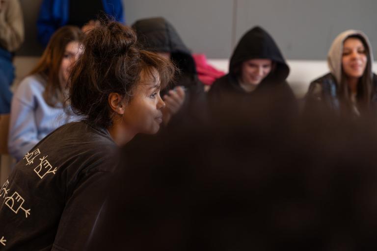 en skådespelare sitter i svart tshirt bland skolelever