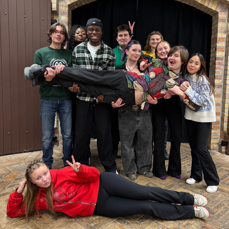 Gruppbild ungdomar som står framför en portöppning och poserar. 